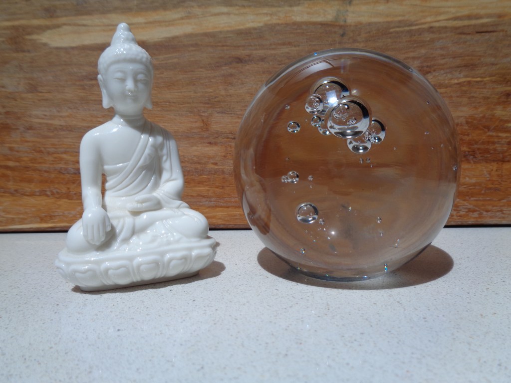 glass orb next to white ceramic buddha